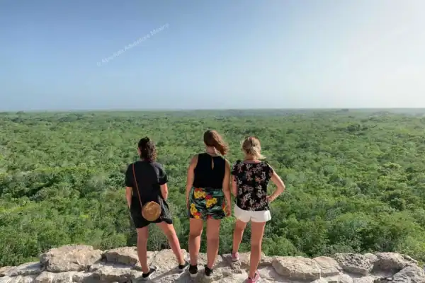 Three friends on  top of Nohoch Mul pyramid with jungle view