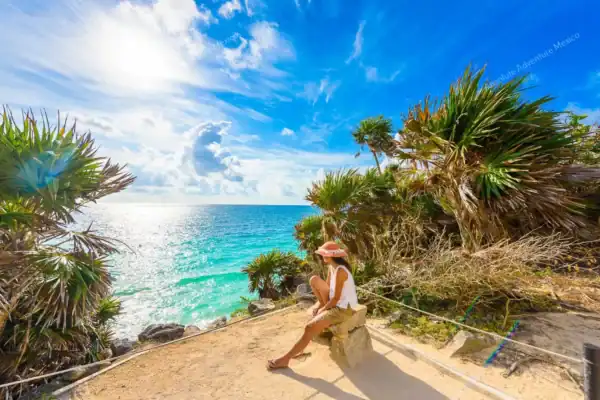 Girl seated by  cliff at Tulum ruins