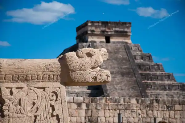 Snake carving at Chichen Itza ball court with Kukulkan pyramid in background