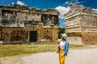 Lady pausing by
  Chichen Itza Nunnery facade