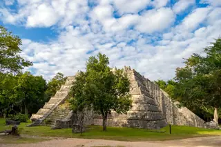 Platform structure
  surrounded by vegetation at Chichen Itza