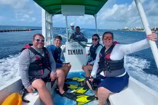 Four people riding
  boat to reef snorkeling spot