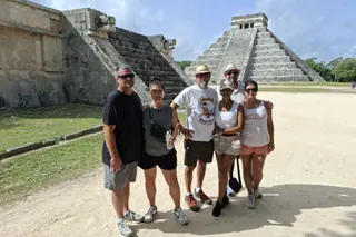 Guests beside the ancient ruins and El Castillo on a Chichen Itza private tour