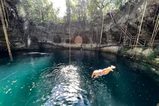 Lady diving into
  X’Canche cenote
