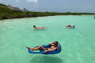 Guest relaxing in
  floating boat at Kaan Luum