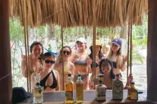 Group of girls in
  swimsuits sipping tequila