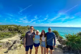 Souvenir photo of
  four visitors at Tulum ruins with ocean backdrop