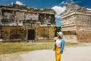 Lady pausing by
  Chichen Itza Nunnery facade